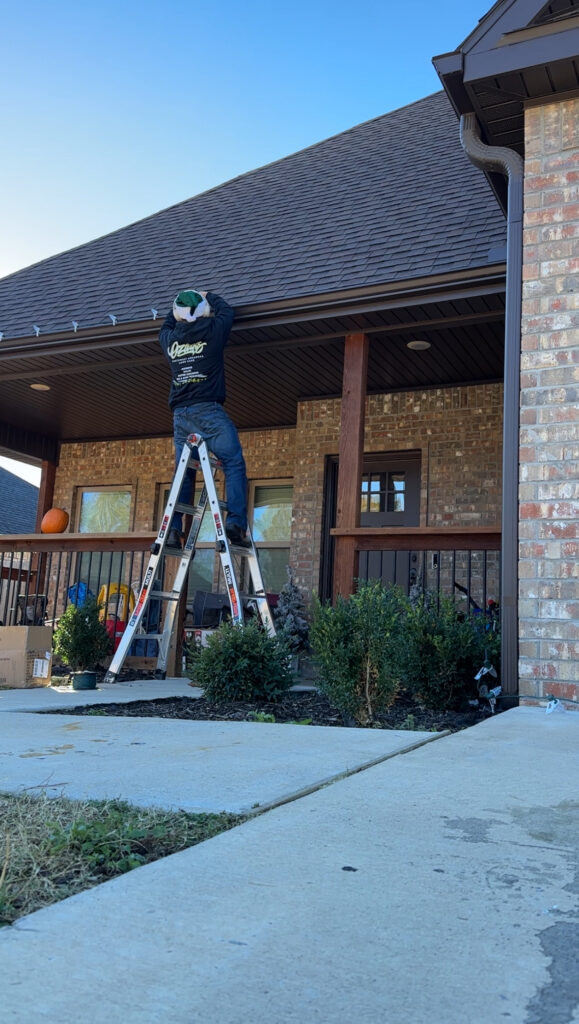 Installing Christmas light services at a residential home on a ladder